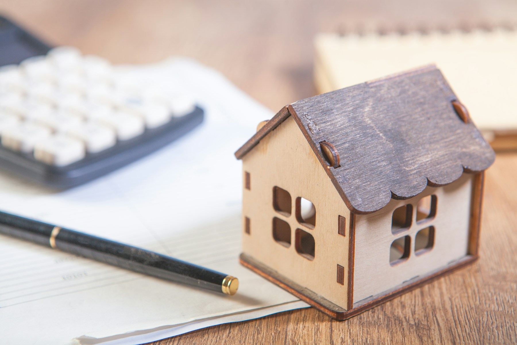 Small house model beside a calculator and paperwork
